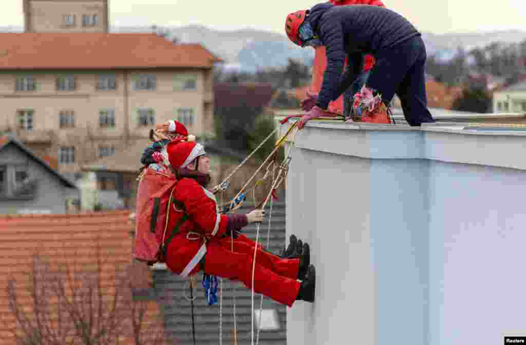 Volunteers dressed in Santa Claus costumes rappel from the roof of Children&#39;s Hospital Srebrnjak to bring gifts to the children, in Zagreb, Croatia.