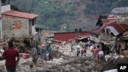 Personas caminan por una calle dañada por inundaciones y deslizamientos de tierra provocados por lluvias torrenciales en el municipio de Tovar, estado de Mérida, Venezuela, el 26 de agosto de 2021.