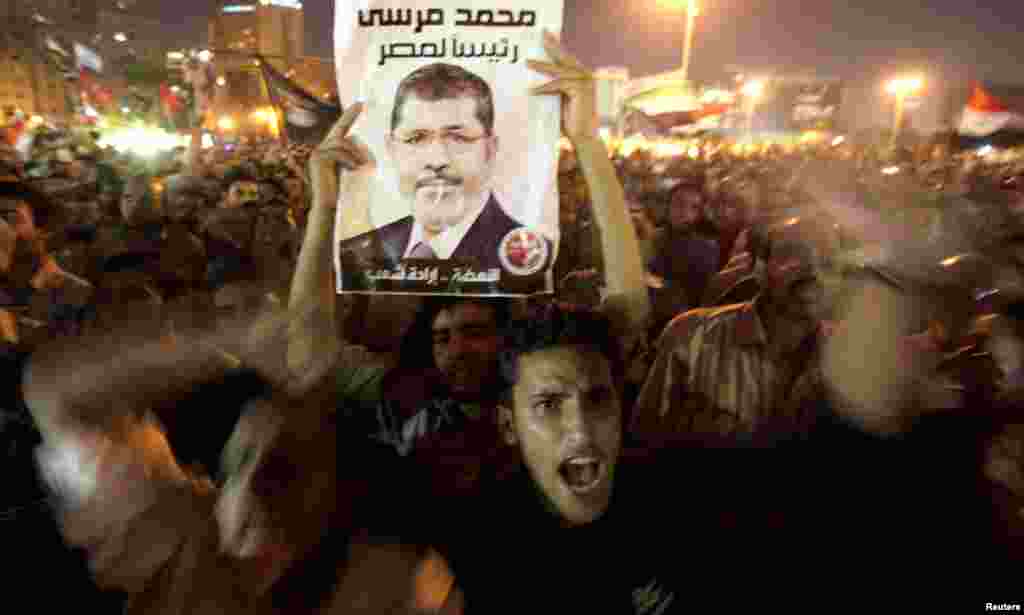 A supporter raises a photo of Mr. Morsi during the celebration of his decision on the dismissal of Hussein Tantawi in Tahrir Square.