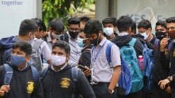 School students wearing face masks as a precaution against COVID-19 wait at a bus stop in Bengaluru, India, Nov. 30, 2021.