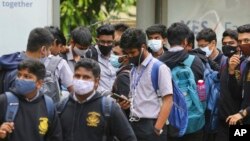 Para siswa di Bengaluru, India, menggunakan masker sebagai langkah pencegahan penularan COVID-19 saat mereka menunggu bis sekolah yang akan datang menjemput pada 30 November 2021. (Foto: AP/Aijaz Rahi)