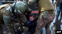 Policías chilenos arrestan a un manifestante durante enfrentamientos con las fuerzas antidisturbios en una protesta el primero de mayo de 2019, en Santiago. AFP/Martin Bernetti.