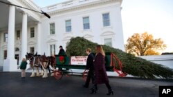 First lady Melania Trump and her son Barron Trump, look at the Wisconsin-grown Christmas tree at the North Portico of the White House in Washington, Nov. 20, 2017. The tree will be displayed in the White House Blue Room.