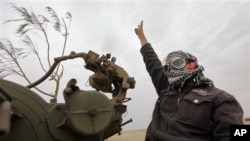 A Libyan rebel fighter manning an anti-aircraft gun flashes the victory sign as his vehicle advances towards the front line, on the outskirts of Ajdabiya, Libya, April 20, 2011