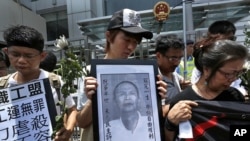 Protesters mourn the death of Chinese labor activist Li Wangyang, seen in picture at center, during a protest outside the Chinese central government's liaison office, in Hong Kong June 7, 2012. 