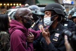 FILE - A protester and a police officer shake hands in the middle of a standoff at a rally in New York City, June 2, 2020, calling for justice over the death of George Floyd.