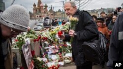 Mourners following the Russian tradition of memorializing a person nine days after a death lay flowers and votive candles at the place where Boris Nemtsov was gunned down near the Kremlin, in Moscow, on Saturday, March 7, 2015. 