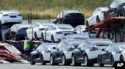 FILE - Tesla cars are loaded onto carriers at the Tesla electric car plant in Fremont, California, May 13, 2020.