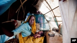 FILE - Aid workers have expressed alarm at poor conditions in South Sudan refugee camps. A woman and baby shelter in a makeshift tent at the Kalma refugee camp.