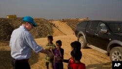 UNICEF Deputy Executive Director Justin Forsyth, left, shares biscuits with Rohingya refugee children as he leaves Balukhali refugee camp 50 kilometres (32 miles) from, Cox's Bazar, Bangladesh Wednesday, Jan. 24, 2018. 