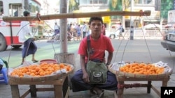 Boy sells fruit on sidewalk in Rangoon, Burma, December 5, 2011