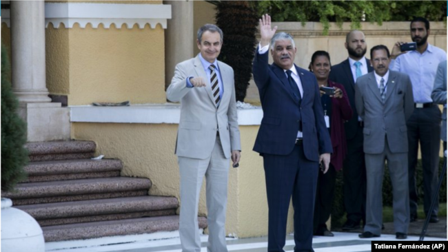 El expresidente del gobierno español José Luis Rodríguez Zapatero, a la izquierda, y el ministro dominicano de Asuntos Exteriores, Miguel Vargas, agradecen a la prensa antes de ingresar al Ministerio de Relaciones Exteriores para participar en las negociaciones.