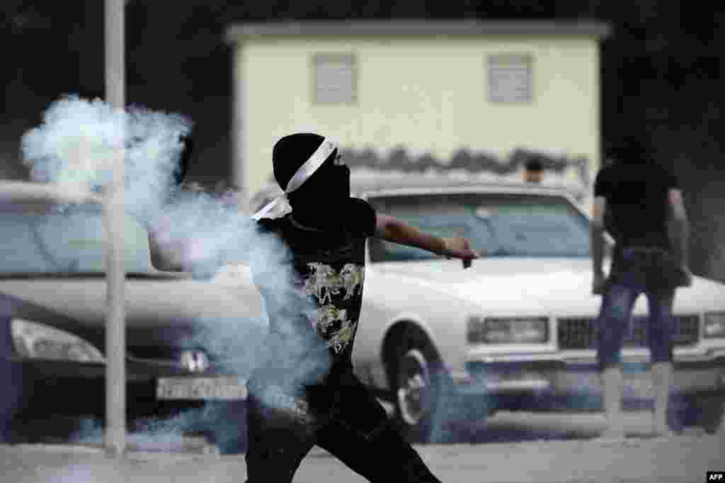  A Bahraini protester throws back a tear gas canister during clashes with riot police following an anti-regime demo heading to &#39;Pearl Square&#39; after a religious procession marking Ashura in the village of Daih, Bahrain. 