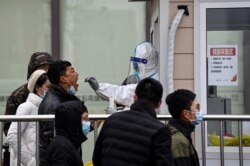 北京街头一处新冠病毒核酸检测点的医护人员在为一名男子进行检测。（2022年1月21日）