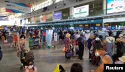 Tourists wear protective masks as they wait to check-in for departure at Da Nang Airport, Vietnam July 26, 2020.