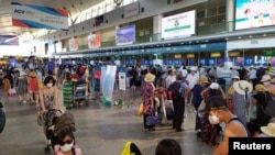 Les touristes portent des masques de protection en attendant l'enregistrement pour le départ à l'aéroport de Da Nang, Vietnam le 26 juillet 2020. Tran Le Lam / VNA via REUTERS. 