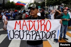 FILE - A man holding a placard that reads "Maduro usurper" takes part in a gathering with members of the Venezuelan National Assembly in Caracas, Venezuela, Jan. 11, 2019.