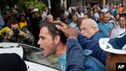 FILE - An opposition activist is detained by Cuban security officers ahead of a march marking International Human Rights Day in Havana, Cuba, Dec. 10, 2014.