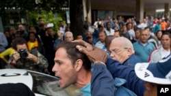 FILE - An opposition activist is detained by Cuban security officers ahead of a march marking International Human Rights Day in Havana, Cuba, Dec. 10, 2014.