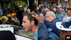 FILE - An opposition activist is detained by Cuban security officers ahead of a march marking International Human Rights Day in Havana, Cuba, Dec. 10, 2014.