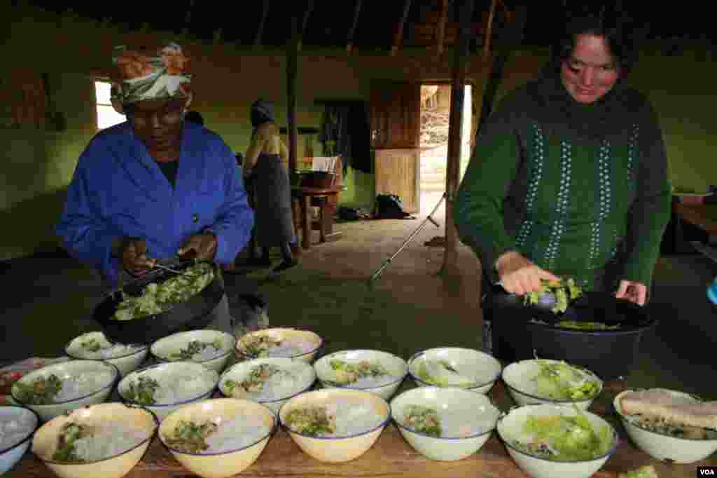 Community elder Mama ka Blondie [left] and Alex Gunther prepare to serve lunch at Ikhaya Loxolo (VOA/Taylor) 