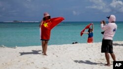 ARSIP – Foto yang diambil tanggal 14 September 2014 memperlihatkan wisatawan China mengambil foto cindera mata seraya memperagakan bendera nasional China saat berkunjung ke Pulau Quanfu, salah satu pulau di Kepulauan Paracel (Foto: AP Photo/Peng Peng, Arsip)