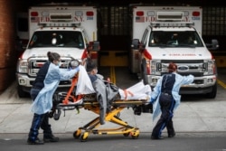 A patient is brought into Wyckoff Heights Medical Center by staff wearing personal protective gear due to COVID-19 concerns, April 7, 2020, in the Brooklyn borough of New York.