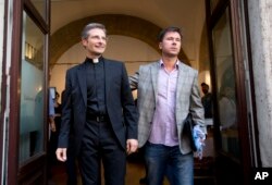Monsignor Krzysztof Charamsa, left, and his boyfriend Eduard, surname not given, pose for a photo as they leave a restaurant after a news conference in downtown Rome, Oct. 3, 2015.