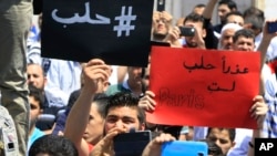 Người biểu tình Lebanon cầm những tấm bảng tiếng Ả Rập với nội dung "#Aleppo" (trái) và "Xin lỗi, Aleppo, các bạn không phải là Paris" (phải) trong một cuộc biểu tình thể hiện tình đoàn kết với Aleppo ở Sidon, Lebanon, ngày 06 tháng 5 năm 2016. 