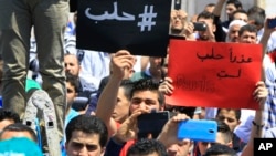 Lebanese protesters hold Arabic placards that read: "#Aleppo," at left, and "Sorry, Aleppo, you are not Paris," at right, during a protest to show solidarity with Aleppo, in Sidon, Lebanon, May 6, 2016. 