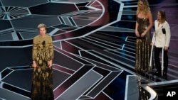 Frances McDormand accepts the award for best performance by an actress in a leading role for "Three Billboards Outside Ebbing, Missouri" as Jennifer Lawrence and Jodie Foster look on from right at the Oscars, March 4, 2018.