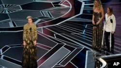 Frances McDormand accepts the award for best performance by an actress in a leading role for "Three Billboards Outside Ebbing, Missouri" as Jennifer Lawrence and Jodie Foster look on from right at the Oscars, March 4, 2018.