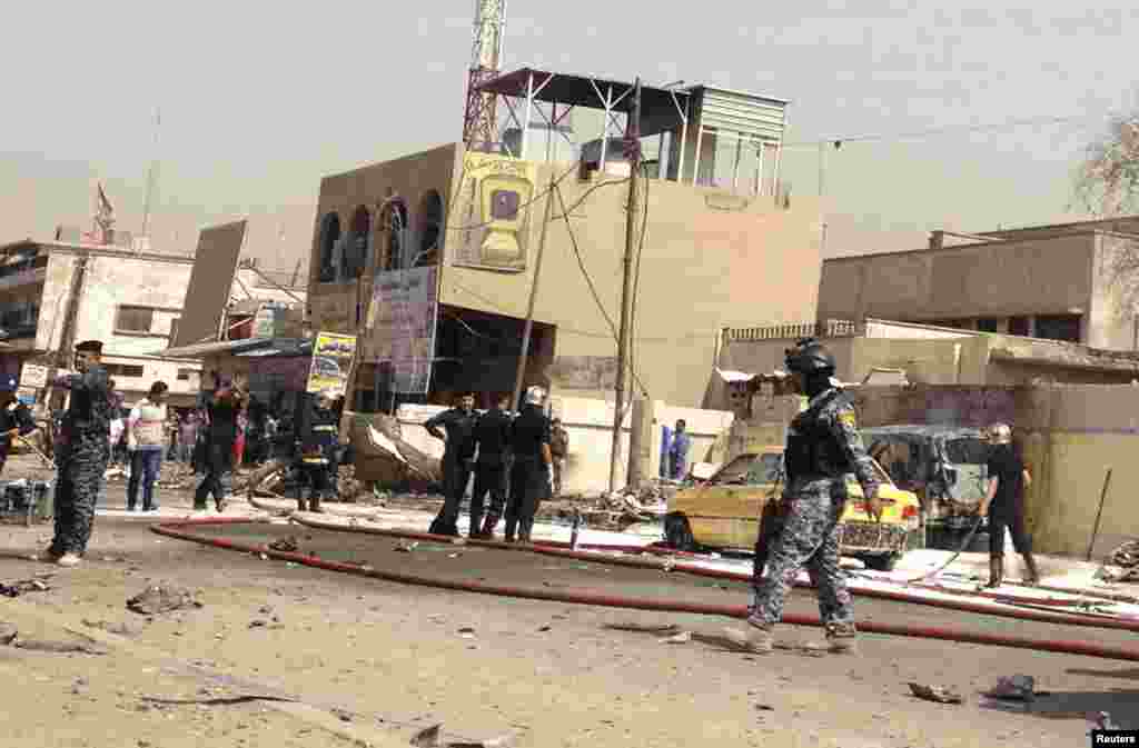 Iraqi security personnel gather around the site of a bomb attack in Baghdad, April 15, 2013. 