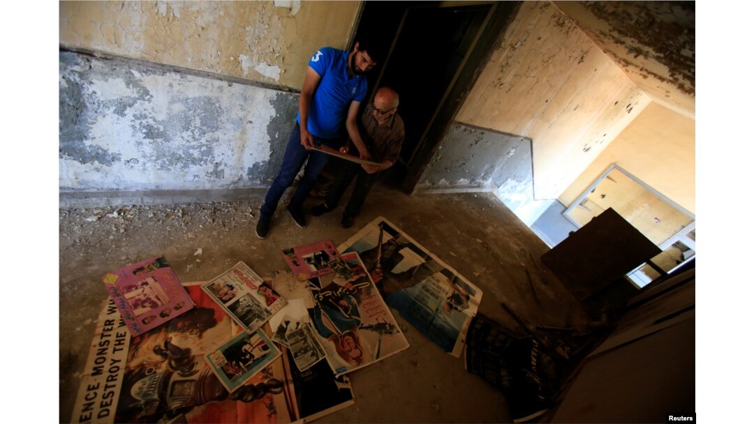 Qassem Istanbouli and another man look at old posters in Al-Ahram, a derelict cinema in Tripoli, Lebanon, July 5, 2017.