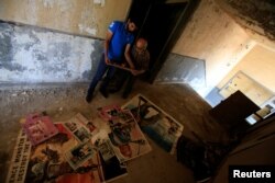 Qassem Istanbouli and another man look at old posters in Al-Ahram, a derelict cinema in Tripoli, Lebanon, July 5, 2017.