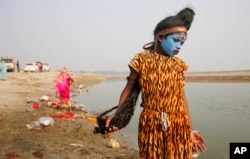 A young Indian boy dressed as Hindu God Shiva walks the banks of the River Ganges looking for alms from devotees on the first day of the nine-day Navratri festival, in Allahabad, India,Tuesday, Oct. 13, 2015.