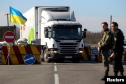 FILE - Ukrainian servicemen stand guard at a checkpoint near the town of Armyansk in Kherson region adjacent to Crimea, March 23, 2014.