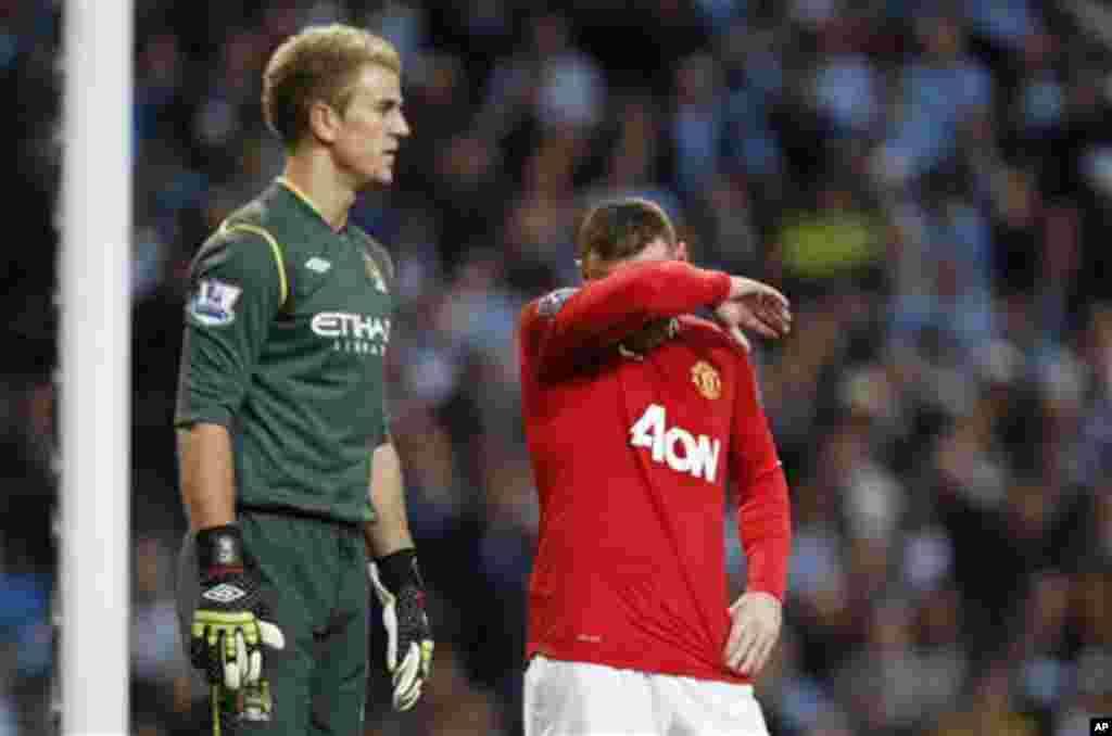 Manchester United's Wayne Rooney, right, wipes his face beside Manchester City's goalkeeper Joe Hart during the English Premier League soccer match between Manchester City and Manchester United at the Etihad Stadium in Manchester, Monday, April 30, 2012. 