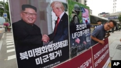 FILE - A photo showing U.S. President Donald Trump and North Korean leader Kim Jong Un is displayed as a member of People's Democratic Party stands to oppose military exercises between the United States and South Korea, near the U.S. Embassy in Seoul, South Korea.