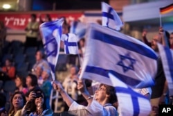 In this photo taken Sept. 29, 2015, an Evangelical Christian holds Israeli flags during a gathering in Jerusalem.