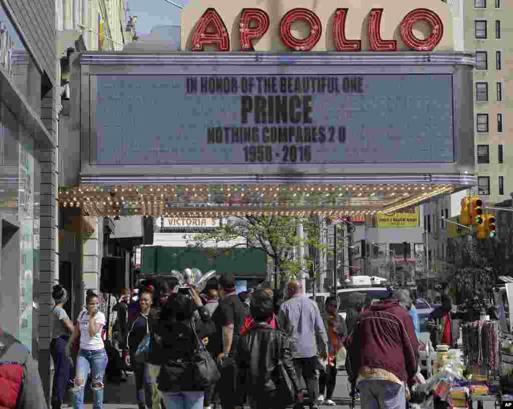 Pedestrians pass New York's Apollo Theater where the marquee displays a message about Prince's death, April 21, 2016. 