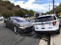 FILE - This photo provided by the Laguna Beach Police Department shows a Tesla sedan, left, in autopilot mode that crashed into a parked police cruiser, in Laguna Beach, Calif., May 29, 2018.