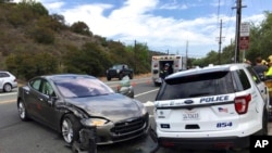 FILE - This photo provided by the Laguna Beach Police Department shows a Tesla sedan, left, in autopilot mode that crashed into a parked police cruiser, in Laguna Beach, Calif., May 29, 2018.