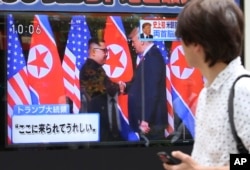 FILE - A man looks at a TV screen showing North Korean leader Kim Jong Un, left, and U.S. President Donald Trump shaking hands before their meeting in Singapore, in Tokyo, June 12, 2018.