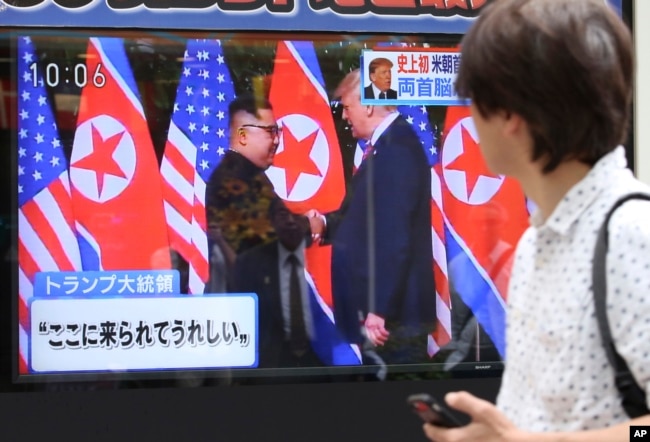 FILE - A man looks at a TV screen showing North Korean leader Kim Jong Un, left, and U.S. President Donald Trump shaking hands before their meeting in Singapore, in Tokyo, June 12, 2018.