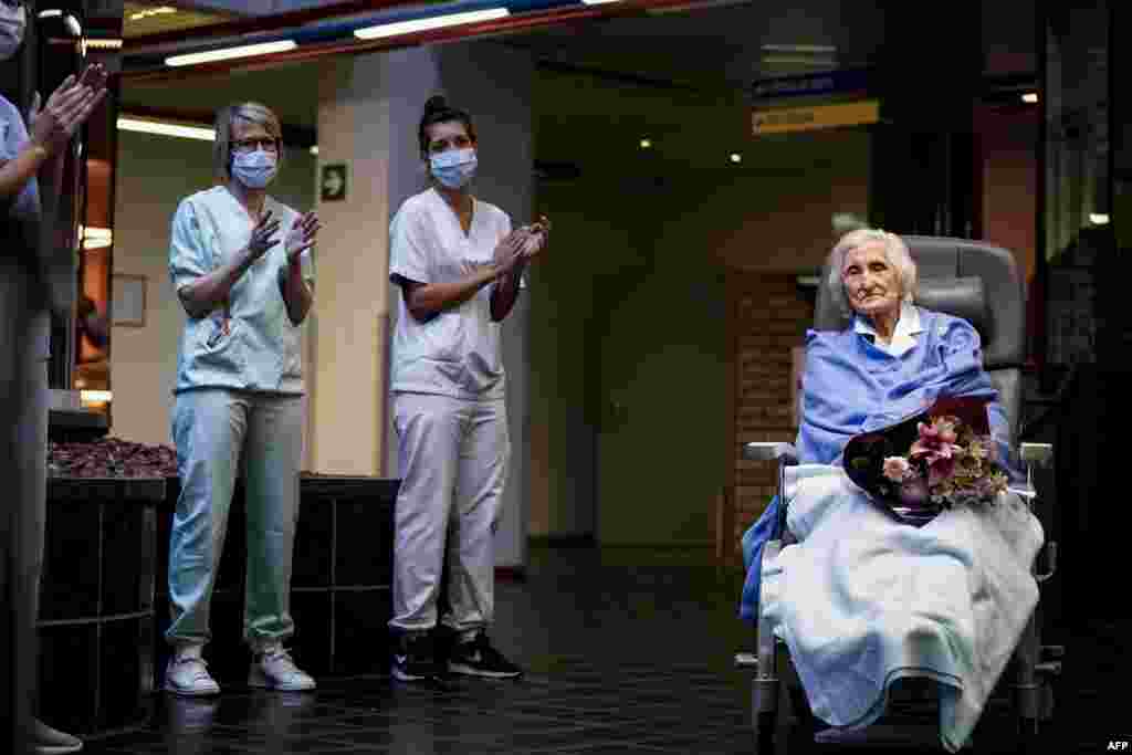 Medical workers clap as 100-year-old patient Julia Dewilde leaves the Bois de l&#39;Abbaye hospital (CHBA) in Seraing, Belgium, after being successfully treated for COVID-19.