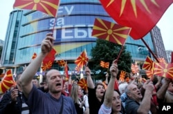 People wave Macedonian flags during a peaceful protest in front of the EU mission building in Skopje, Macedonia, April 28, 2017. About 2,000 protesters gathered in Macedonia’s capital Skopje to demand new elections to try and break the country’s political deadlock, a day after violent protests inside the country’s parliament.