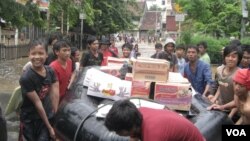 Warga korban banjir di Kampung Pulo dan Bukit Duri gotong royong mengangkut berbagai logistik ke tempat pengungsian, Kamis 17/1 (foto: VOA/Andylala).