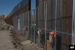 Workers continue work raising a taller fence in the Mexico-US border separating the towns of Anapra, Mexico and Sunland Park, New Mexico, Jan. 25, 2017.