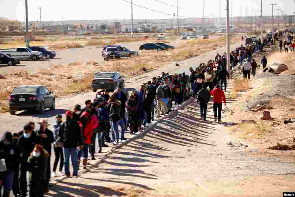 Teachers and school workers line up for a third shot of the Moderna COVID-19 vaccine during a mass vaccination program outside a university in Ciudad Juarez, Mexico, Jan. 12, 2022.